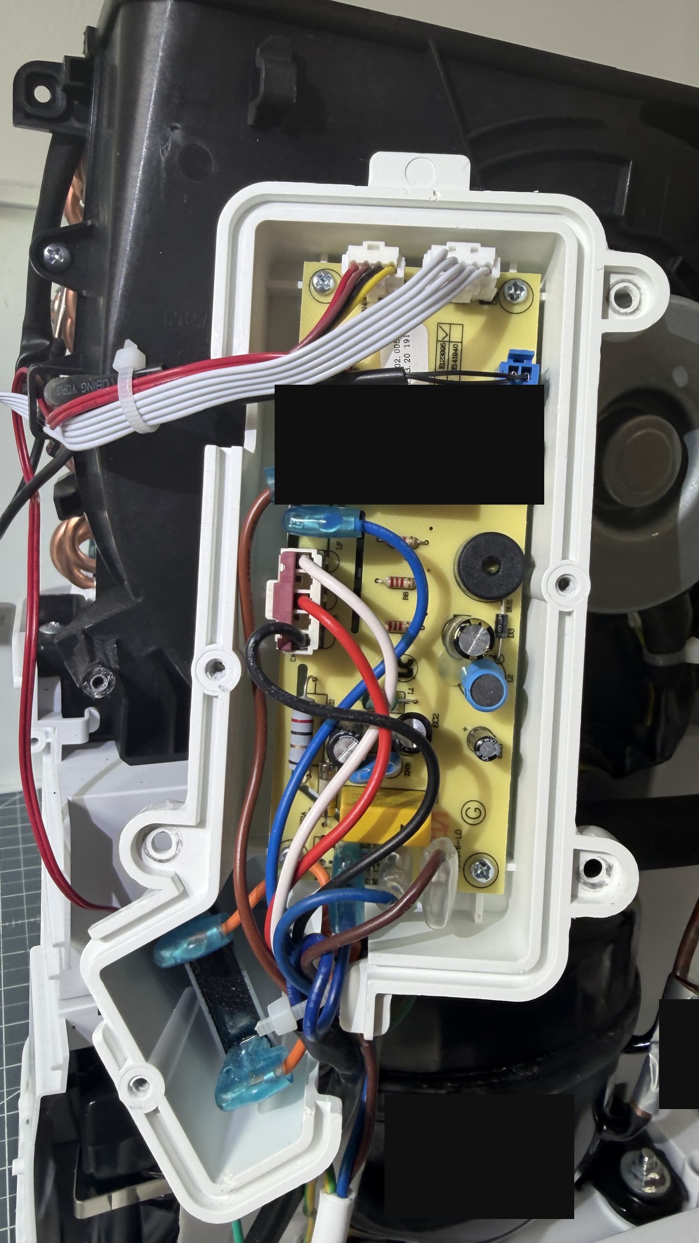 Opened plastic housing containing the power supply unit of an identical appliance, circuit board with components and wiring.