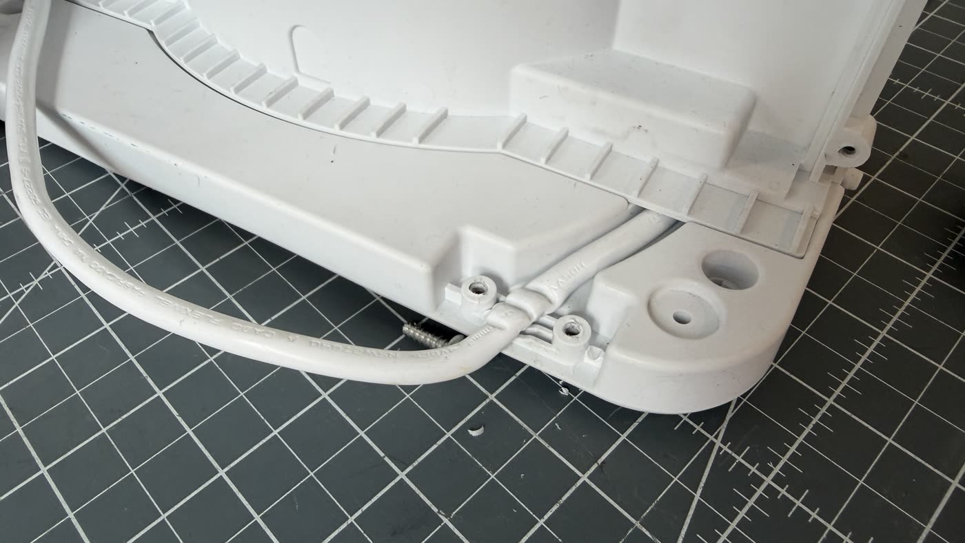 Close-up of the strain relief of an identical appliance: the mains lead is severely pinched between plastic ribs.